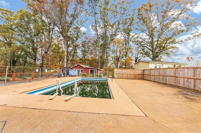 view of swimming pool featuring a patio and an outbuilding