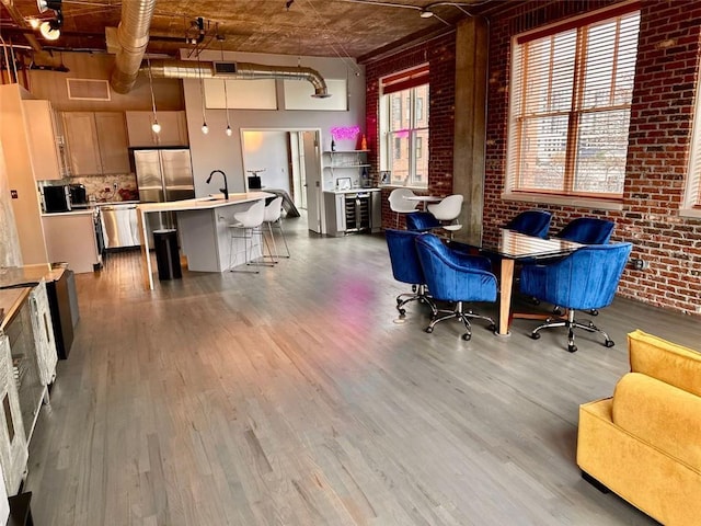 dining room featuring hardwood / wood-style floors, a towering ceiling, brick wall, and sink