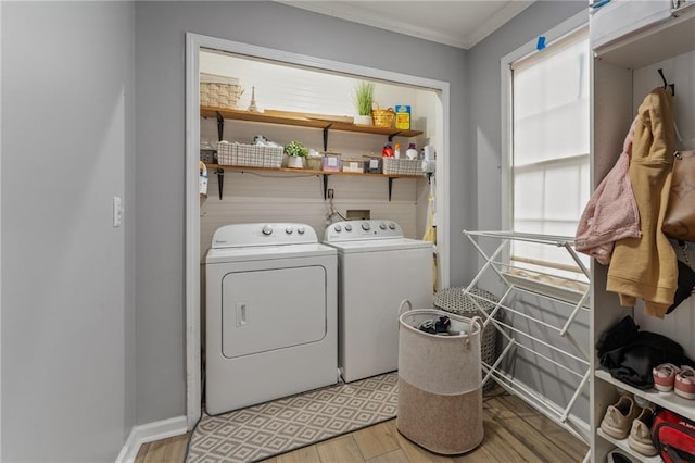 clothes washing area featuring independent washer and dryer, crown molding, plenty of natural light, light wood finished floors, and laundry area