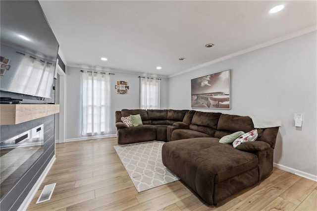 living area featuring ornamental molding, a tile fireplace, visible vents, and light wood-type flooring