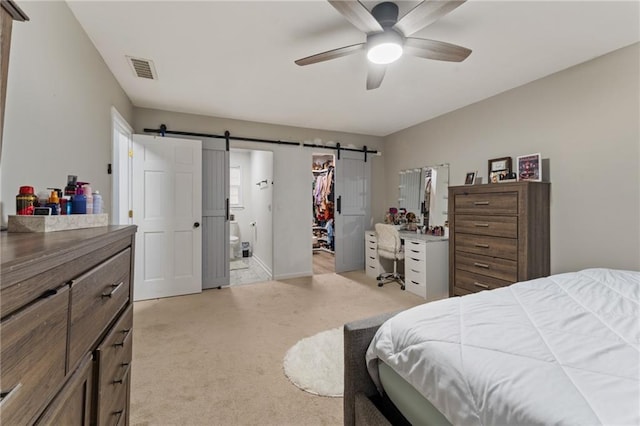 bedroom featuring connected bathroom, a barn door, light carpet, a walk in closet, and visible vents