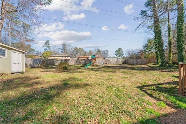 view of yard with an outdoor structure, a shed, a playground, and a fenced backyard
