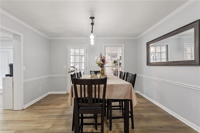 dining space featuring crown molding, wood finished floors, and baseboards