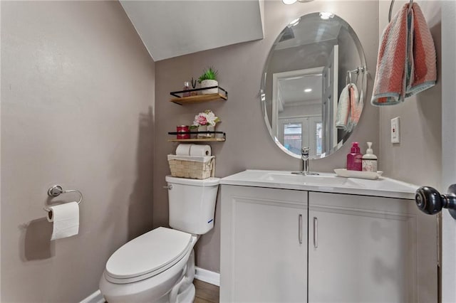 half bathroom featuring baseboards, vaulted ceiling, toilet, and vanity