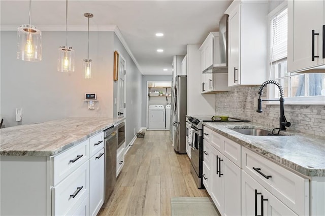 kitchen with wall chimney range hood, independent washer and dryer, a sink, appliances with stainless steel finishes, and backsplash