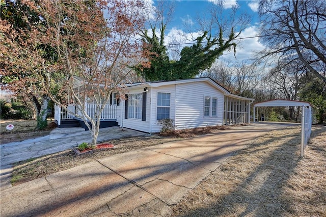 view of front facade featuring covered porch, concrete driveway, and a carport