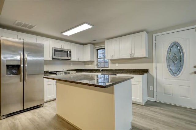 kitchen featuring a kitchen island, white cabinetry, appliances with stainless steel finishes, and light hardwood / wood-style flooring