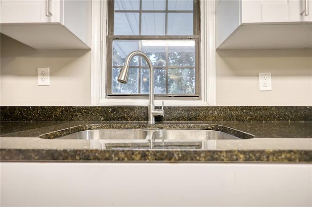 details featuring white cabinets, dark stone countertops, and sink