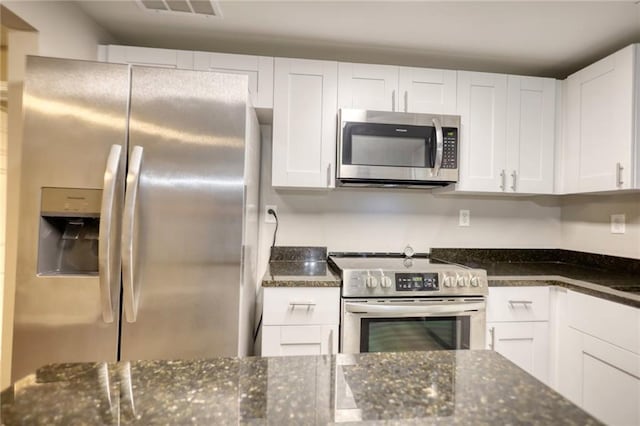 kitchen featuring white cabinetry, appliances with stainless steel finishes, and dark stone counters