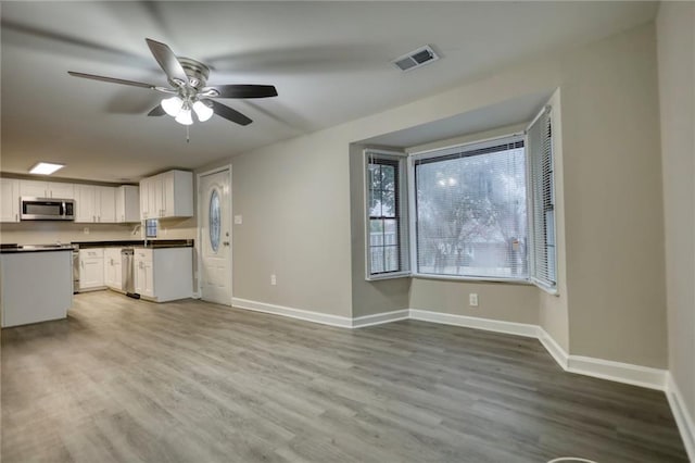 kitchen with white cabinetry, ceiling fan, stainless steel appliances, and light wood-type flooring