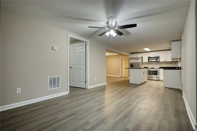 unfurnished living room featuring hardwood / wood-style flooring, ceiling fan, and sink