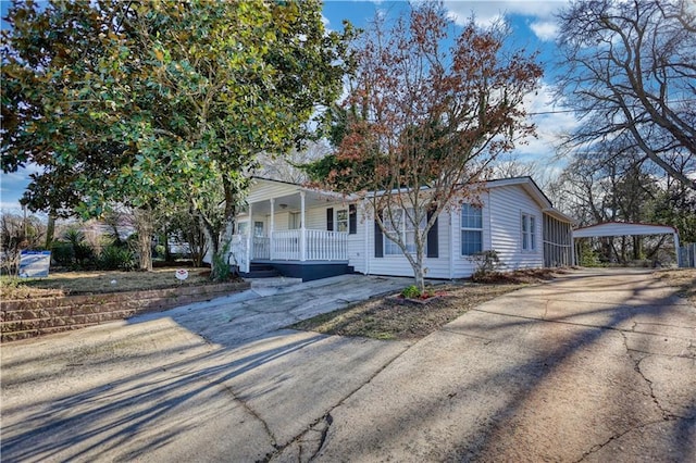 ranch-style house with driveway, a porch, and a detached carport