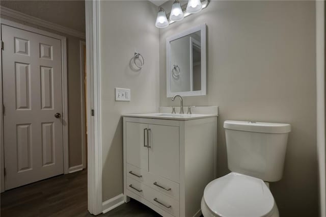 bathroom featuring toilet, vanity, ornamental molding, and hardwood / wood-style flooring