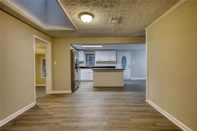 kitchen featuring sink, crown molding, stainless steel refrigerator with ice dispenser, hardwood / wood-style flooring, and white cabinetry