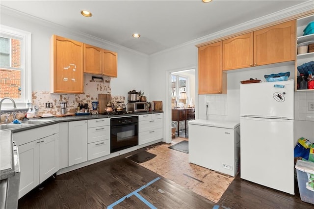 kitchen with wood finished floors, oven, freestanding refrigerator, fridge, and a sink