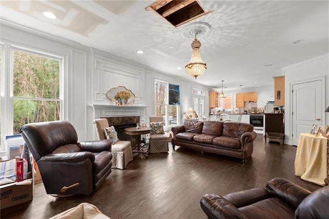 living area featuring dark wood-style floors, recessed lighting, a decorative wall, a premium fireplace, and ornamental molding