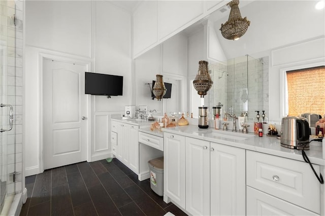 bathroom featuring a decorative wall, wood finished floors, vanity, vaulted ceiling, and a shower stall