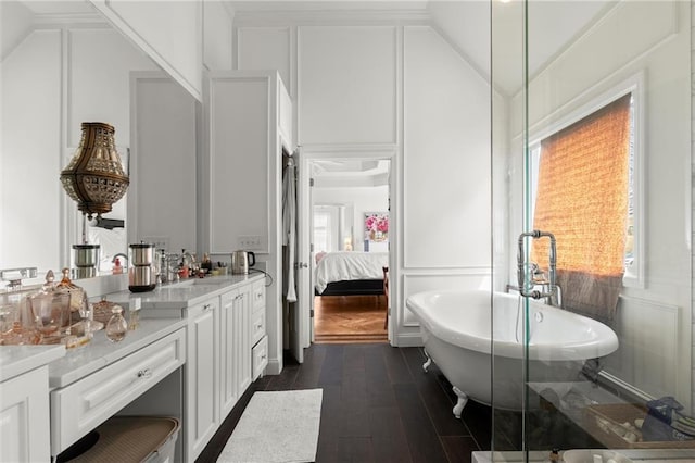 full bath featuring plenty of natural light, vaulted ceiling, a decorative wall, and ensuite bath