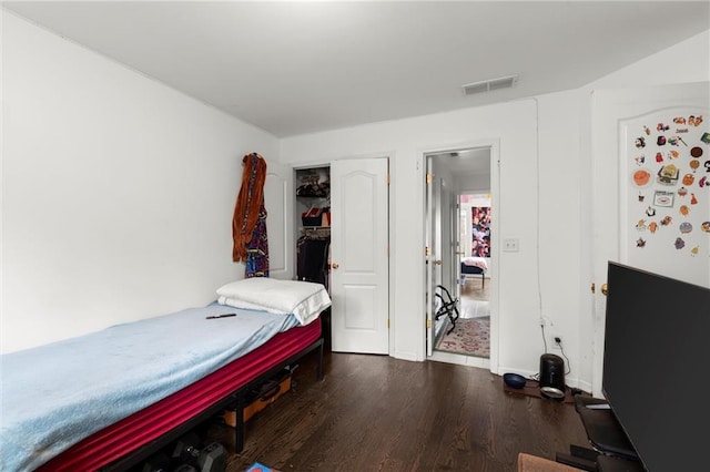 bedroom featuring dark wood-style floors, a closet, and visible vents