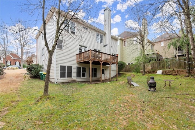 rear view of property featuring a deck, a lawn, and fence