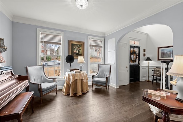 living area featuring dark wood-style floors, baseboards, arched walkways, and ornamental molding