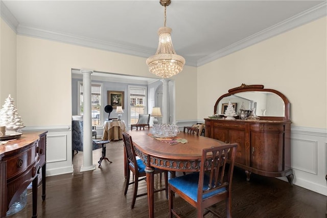 dining space featuring decorative columns, a wainscoted wall, dark wood-style flooring, crown molding, and a notable chandelier