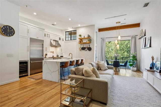 living area featuring wine cooler, recessed lighting, light wood-style flooring, and visible vents