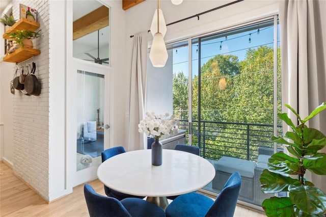 dining room featuring plenty of natural light, brick wall, and light wood finished floors