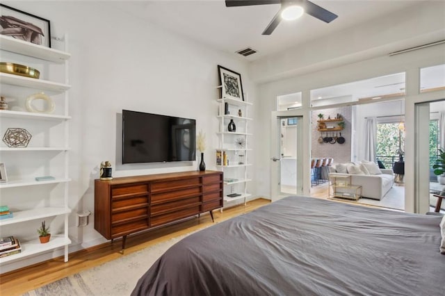 bedroom with visible vents, access to outside, wood finished floors, baseboards, and ceiling fan