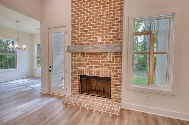 460 Ridge Point Dr, Monticello, GA 31064 - unfurnished living room featuring baseboards, wood finished floors, a chandelier, and a fireplace