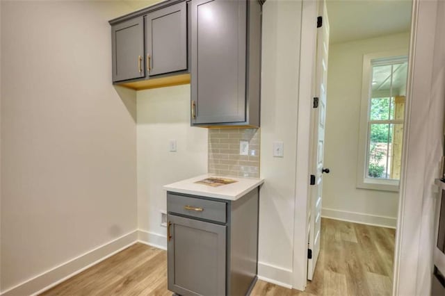 460 Ridge Point Dr, Monticello, GA 31064 - kitchen featuring gray cabinets, light wood finished floors, light countertops, decorative backsplash, and baseboards