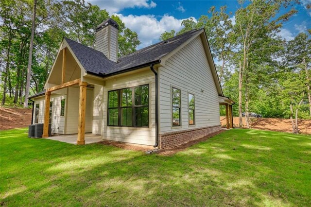 460 Ridge Point Dr, Monticello, GA 31064 - view of side of property featuring a patio area, a yard, a chimney, roof with shingles, and brick siding