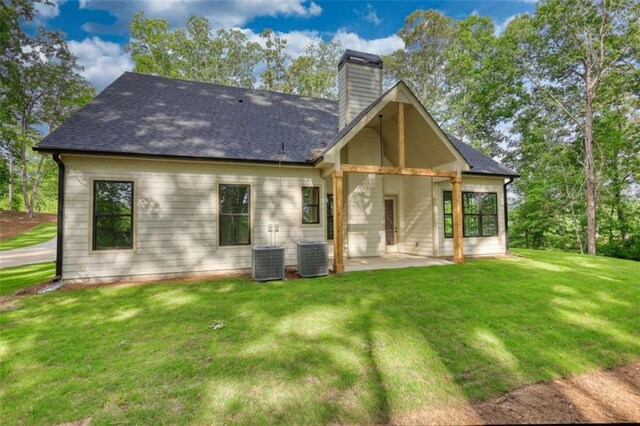 460 Ridge Point Dr, Monticello, GA 31064 - rear view of house featuring a patio, a chimney, a lawn, central AC, and a shingled roof
