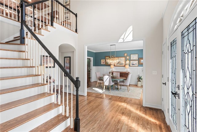 foyer entrance with stairs, crown molding, a towering ceiling, and wood finished floors