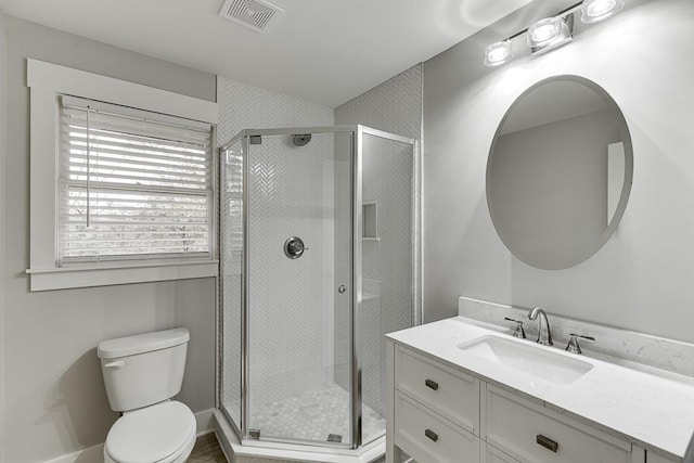 bathroom with vanity, toilet, and a shower with door