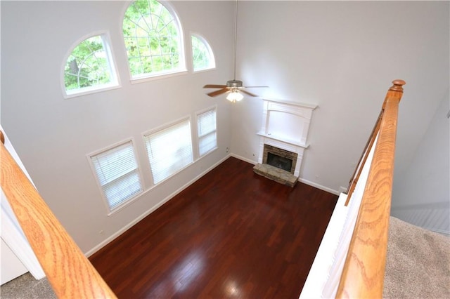 living room featuring a towering ceiling, a fireplace, dark hardwood / wood-style floors, and ceiling fan