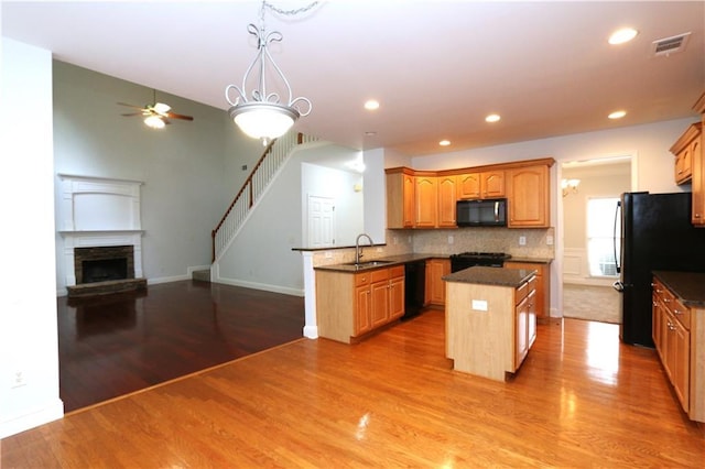 kitchen featuring black appliances, sink, a center island, kitchen peninsula, and light hardwood / wood-style flooring