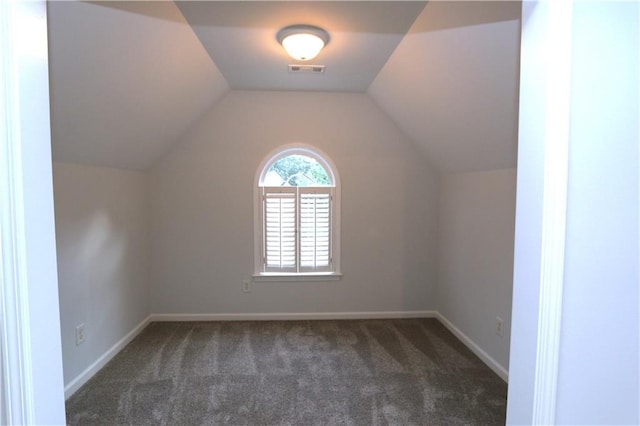 additional living space featuring vaulted ceiling and dark colored carpet