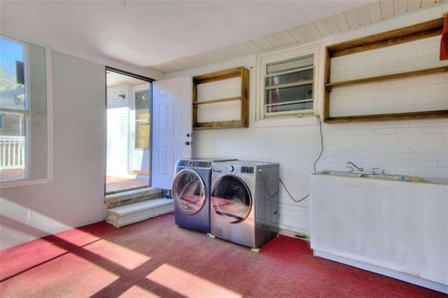 laundry room with washer and dryer, carpet floors, and brick wall