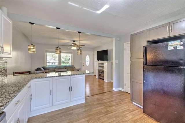 kitchen with white cabinetry, ceiling fan, black refrigerator, and light hardwood / wood-style flooring