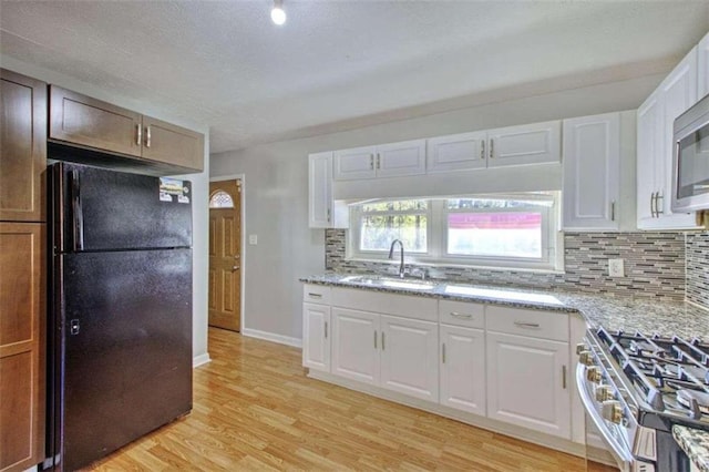 197 Dixboro Dr, Jonesboro, GA 30238 - kitchen with freestanding refrigerator, a sink, decorative backsplash, stainless steel range with gas stovetop, and light wood-type flooring