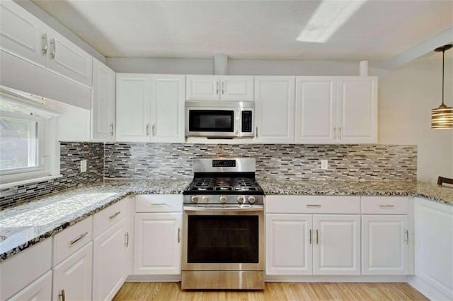 kitchen featuring white cabinets, pendant lighting, and stainless steel appliances