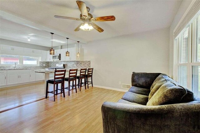 living room with ceiling fan, sink, and light hardwood / wood-style flooring