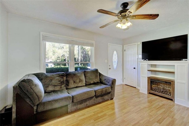 living room with a textured ceiling, light wood-type flooring, and ceiling fan