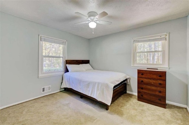 carpeted bedroom with ceiling fan and a textured ceiling