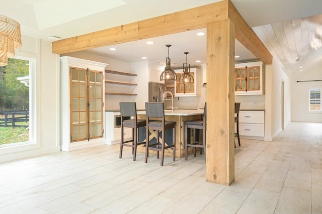 kitchen featuring lofted ceiling, pendant lighting, a healthy amount of sunlight, and stainless steel refrigerator with ice dispenser