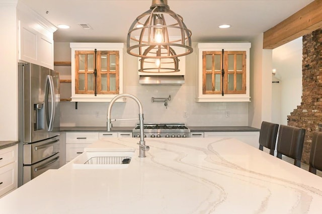 kitchen featuring white cabinets, decorative backsplash, appliances with stainless steel finishes, dark stone counters, and decorative light fixtures