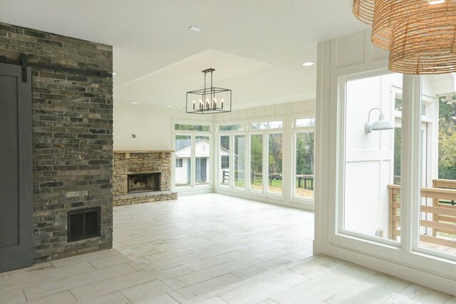 unfurnished living room featuring a barn door, a fireplace, and plenty of natural light