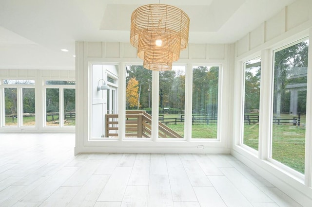 unfurnished sunroom featuring a chandelier and a tray ceiling