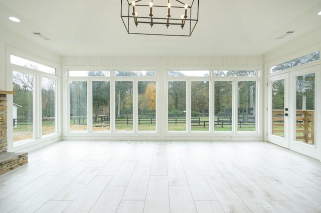 unfurnished sunroom with a notable chandelier and a stone fireplace